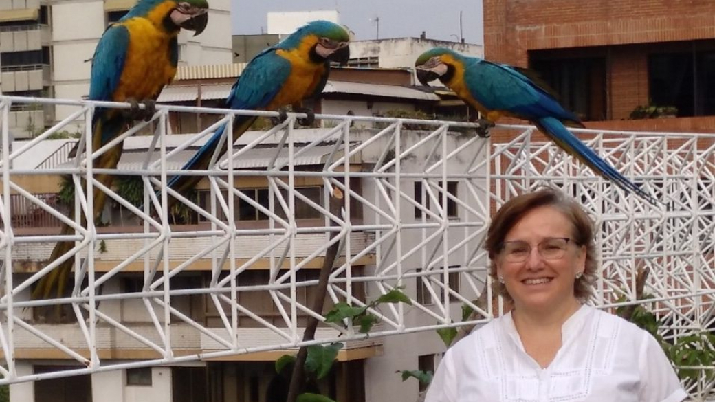 Sonia posa junto a las guacamayas, aves típicas de estos lugares